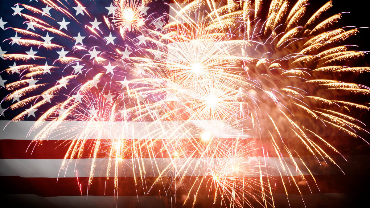 Exploding fireworks are seen against a background of the American flag.