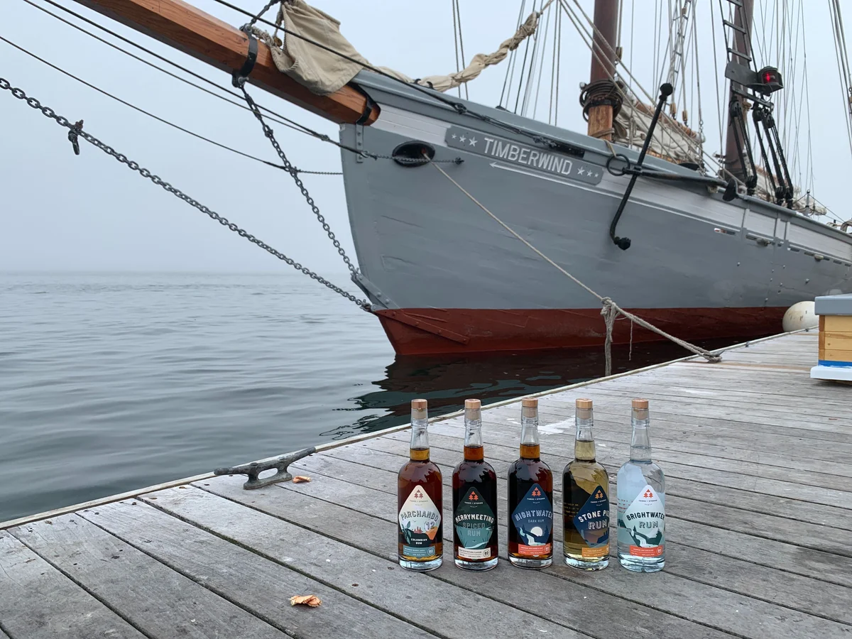 A variety of rums sit on the dock in front of the boat Timberwind to promote the rum history and tasting cruise with Portland Schooner Co.